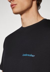 Black cotton T-shirt with a crew neckline, featuring a light blue "icebreaker" logo embroidered on the left chest area.