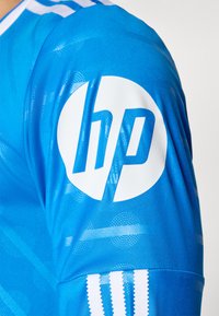 Blue sports jersey sleeve with white HP logo and three white vertical stripes near the cuff.