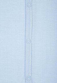 Helles blaues geripptes Stoff mit vertikaler Textur; verfügt über eine Reihe von runden Knöpfen entlang der Mitte, die mit der Farben des Stoffes harmonieren.