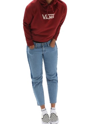 Felpa rossa con logo "VANS", jeans in denim blu chiaro e scarpe slip-on a scacchi bianchi e neri. Outfit casual con una vestibilità rilassata.