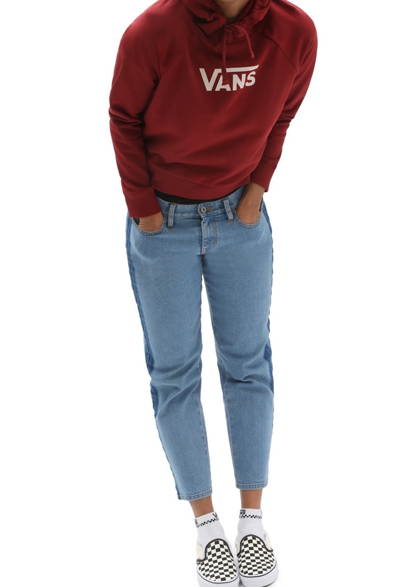 Felpa rossa con logo "VANS", jeans in denim blu chiaro e scarpe slip-on a scacchi bianchi e neri. Outfit casual con una vestibilità rilassata.