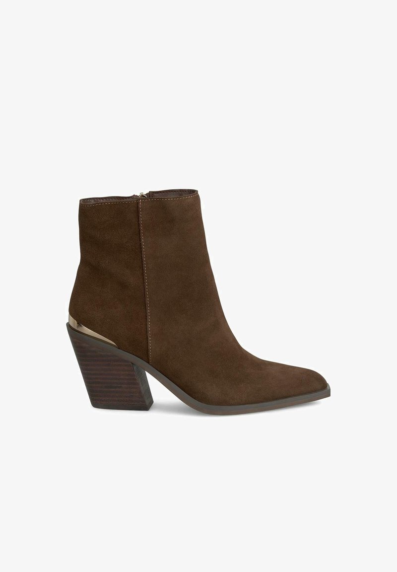 Bruine suede enkellaars met een spitse neus, ritssluiting en een geometrische blokhak met een donkere houtstructuur en metalen accent.