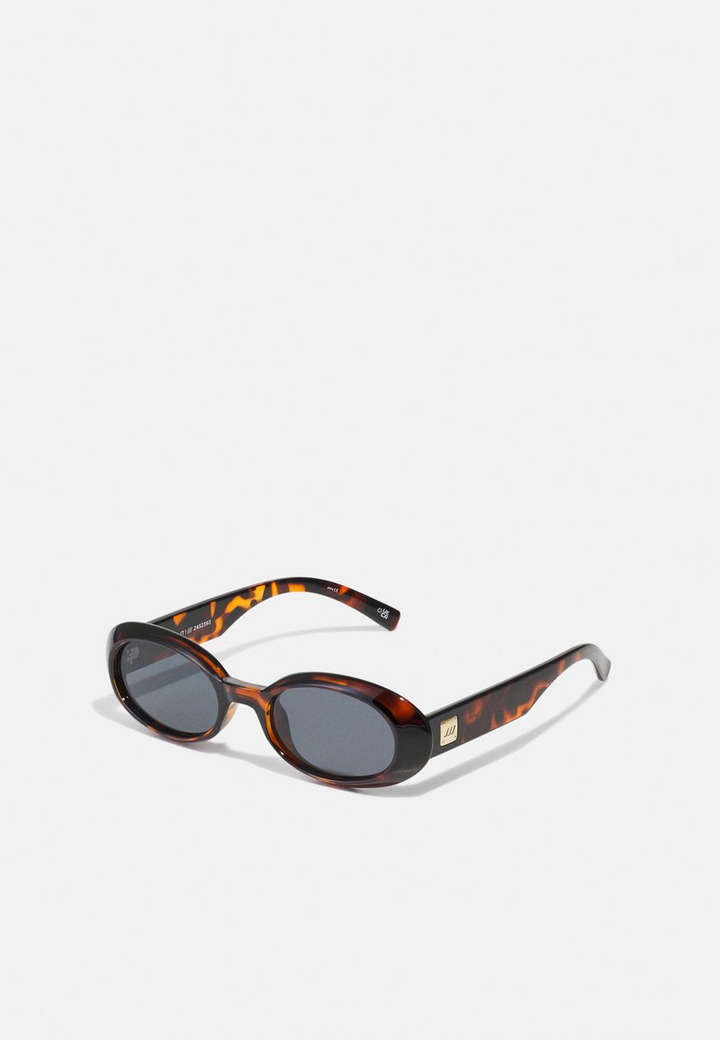 Brown tortoiseshell sunglasses with oval lenses and dark grey tint. Features a gold-tone accent on the temples. Smooth plastic texture.