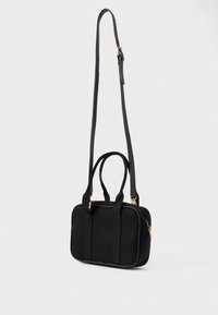 Μικρή μαύρη ορθογώνια τσάντα με δύο κοντές λαβές και έναν μακρύ ρυθμιζόμενο ιμάντα ώμου, με χρυσές λεπτομέρειες στη φερμουάρ και τα αξεσουάρ.