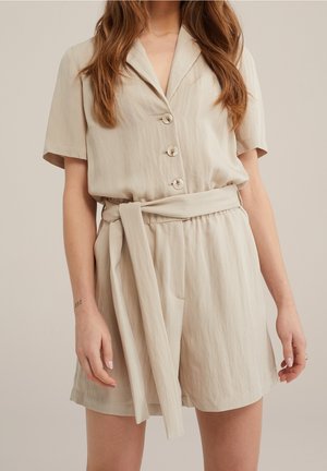 Beige short-sleeve romper met knoopsluiting en een riem van dezelfde stof. Gemaakt van een gestructureerd, lichtgewicht materiaal met zijzakken.