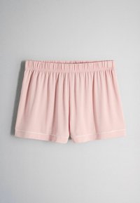 Shorts da donna a vita elasticizzata di colore rosa chiaro con bordatura bianca lungo l'orlo, mostrati distesi su uno sfondo grigio.