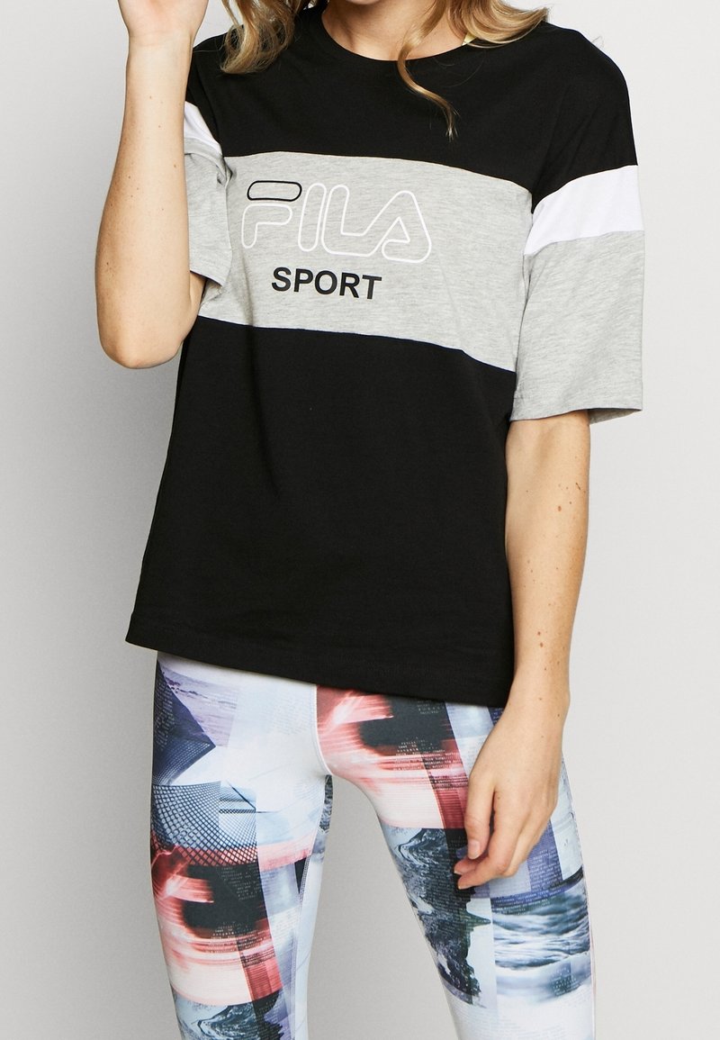 T-shirt noir et gris à manches courtes de Fila Sport en tissu léger avec impression du logo, porté avec des leggings colorés à motifs.