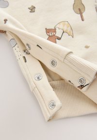 Body en coton crème avec motif d'ours et de parapluie dessin animé. Doté de boutons-pression argentés et de poignets côtelés pour un ajustement parfait.