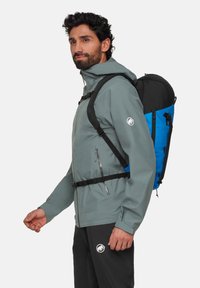 Grå vattentät jacka med justerbara manschetter och dragkedjor; svart och blå ryggsäck med flera fack och en vadderad rygg.