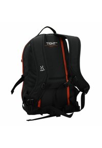 Mochila de tela negra con acentos naranjas, correas ajustables acolchadas, hebillas laterales y logo. Presenta un diseño compacto y ergonómico.