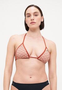 Triangular bikini top with geometric pattern in red and beige, featuring thin straps. Includes a small logo detail on the left side.