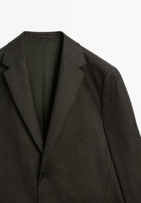 Mörkgrå kavaj med en skräddarsydd design, strukturerade slag, enkel svart knäppning och en mjuk tygstruktur.