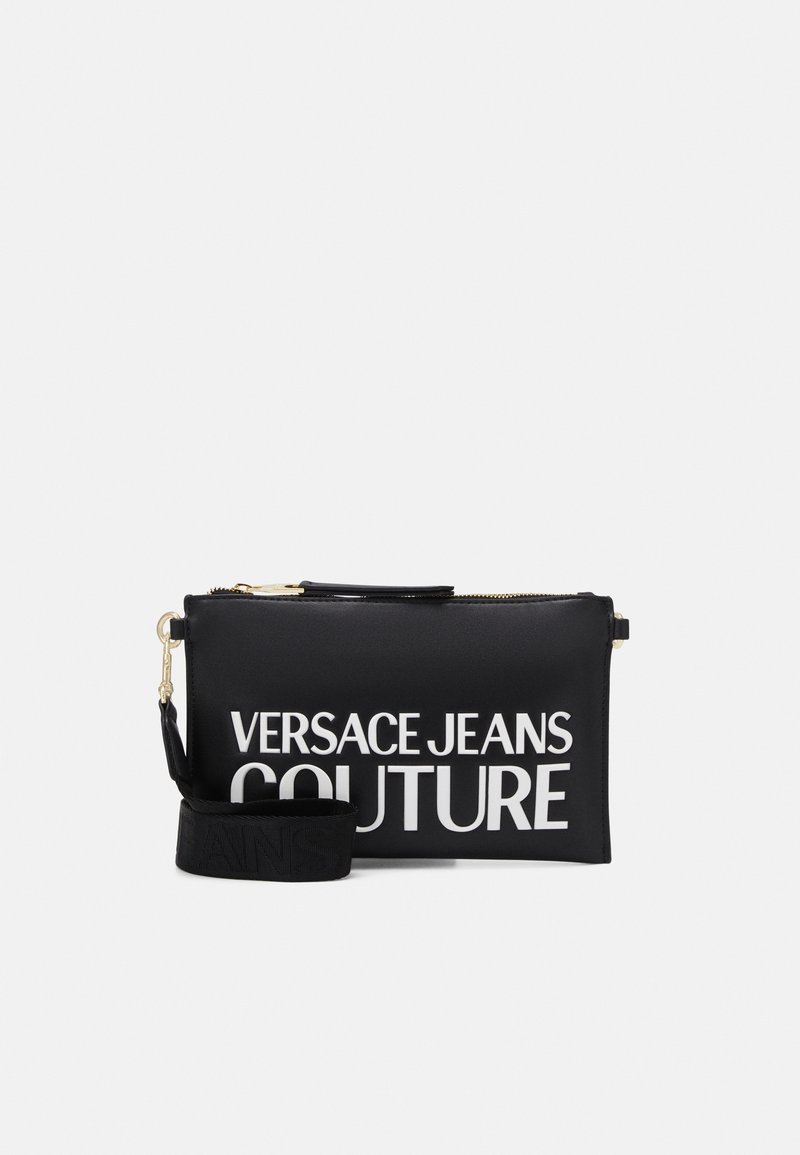 Sort rektangulær pouch med lynlås og aftagelig rem, mærket med stor hvid tekst "VERSACE JEANS COUTURE" foran.