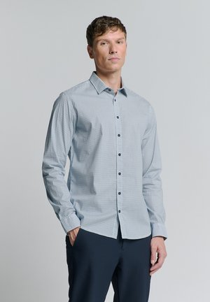 Blauw patroon dat overhemd met kraag, lange mouwen en donkere knopen, gecombineerd met donkere broek. Glad textuur.