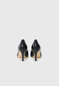Sorte lærhøye sko med en glatt tekstur og spiss tå, med en slank stilettheell og et minimalistisk design.