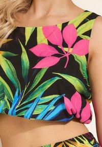 Wielokolorowy top z krótkim rękawem na czarnym tle z żywymi tropikalnymi liśćmi w odcieniach zieleni, niebieskiego i różowego. Miękki, lekki materiał.