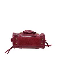 Rote Lederhandtasche mit runder Form, strukturierten Oberflächen, kontrastierenden Messingbeschlägen und dekorativen Seitenfransen.