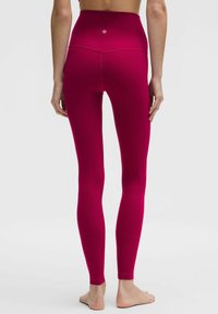 Legginsy z wysokim stanem, dopasowane do sylwetki, w żywym różowym kolorze, o gładkiej fakturze, bez widocznych wzorów czy detali z metalu.
