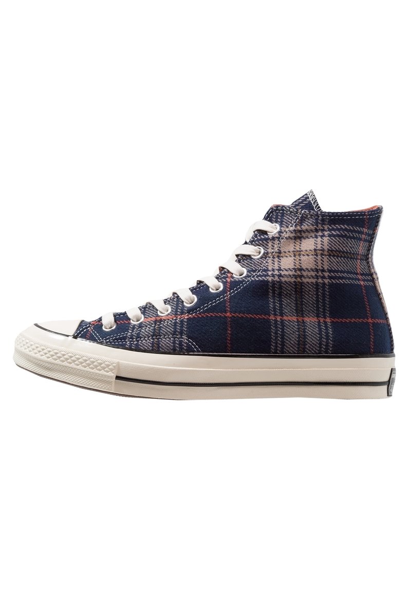 Hochformatige Sneakers aus kariertem Stoff in Marineblau, Beige und Rot. Weiße Gummisohle mit schwarz gestreiftem Detail. Sechs Schnürsenkel.