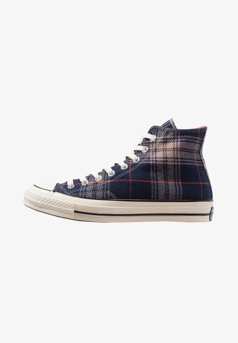 Hochformatige Sneakers aus kariertem Stoff in Marineblau, Beige und Rot. Weiße Gummisohle mit schwarz gestreiftem Detail. Sechs Schnürsenkel.