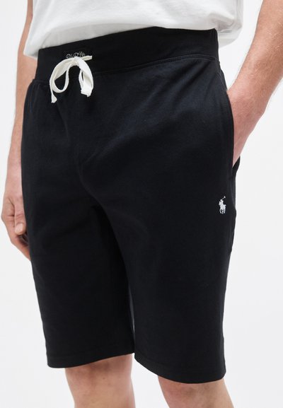 Juodi medvilniniai šortai su raišteliu juosmens srityje, šoninėmis kišenėmis ir mažu baltu logotipu ant apatinės kojos dalies. Lygus paviršius ir kelių ilgio dizainas.