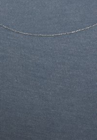 Close-up of blue ribbed fabric with a curved metallic silver seam near the top edge.