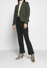 Olive green blazer with two buttons, black high-waisted jeans, and metallic snake-print ankle boots with a pointed toe and stiletto heel.