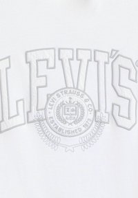 Vit t-shirt med grå broderad text "LEVI'S" och en cirkulär logotyp med lagerblad och "Etablerad 1873" nedanför.