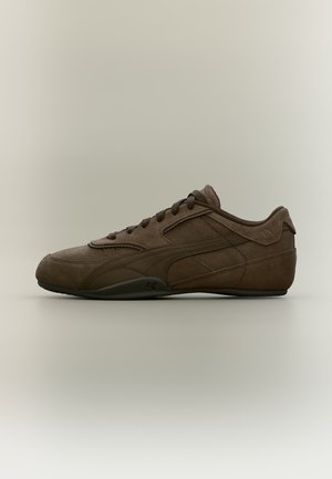 Baskets Puma en daim brun foncé avec lacets, logo latéral et semelle en caoutchouc profilée basse sur fond neutre.