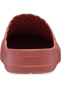 Rode instapklompen met een textuur aan de binnenkant en het "crocs"-logo in reliëf op de hiel, gezien vanuit de achterkant.