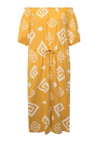 Keltainen olkapäältä avattu mekko, jossa on valkoisia geometrisia kuvioita. Mekossa on lyhyet joustavat hihat, kiristettävä vyötärö ja rento malli.