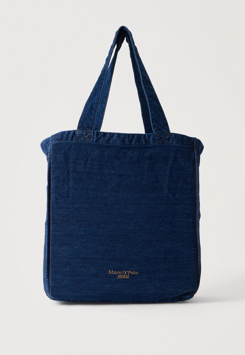 Sac cabas en denim bleu avec deux anses et un petit texte doré « Marc O'Polo Denim » au centre devant.