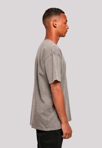 Graues Baumwoll-T-Shirt mit lockerer Passform, kurzen Ärmeln und runder Ausschnitt. Verfügt über dezente Verblassungen und sichtbare Nähte entlang der Kanten.