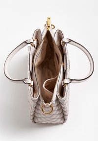 Weiße gesteppte Handtasche mit zwei Griffen, goldener Reißverschluss und Ringen, die das leere beige Innere mit Logo-Muster und mehreren Fächern zeigt.
