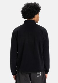 Zwarte fleece jas met een opstaande kraag, lange mouwen en een zachte textuur. Kenmerkt zich door een rechte zoom en heeft geen zichtbare logo's of patronen.