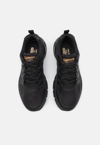 Svarta Skechers-sneakers med en texturerad ovandel och snörningsdesign, med en tydligt synlig logotyp på tungan.