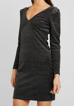 Schwarzes Kleid mit langen Ärmeln, V-Ausschnitt, aus weichem Stoff mit einem Muster aus vertikalen weißen Streifen. Sanfte Textur und taillierte Silhouette.