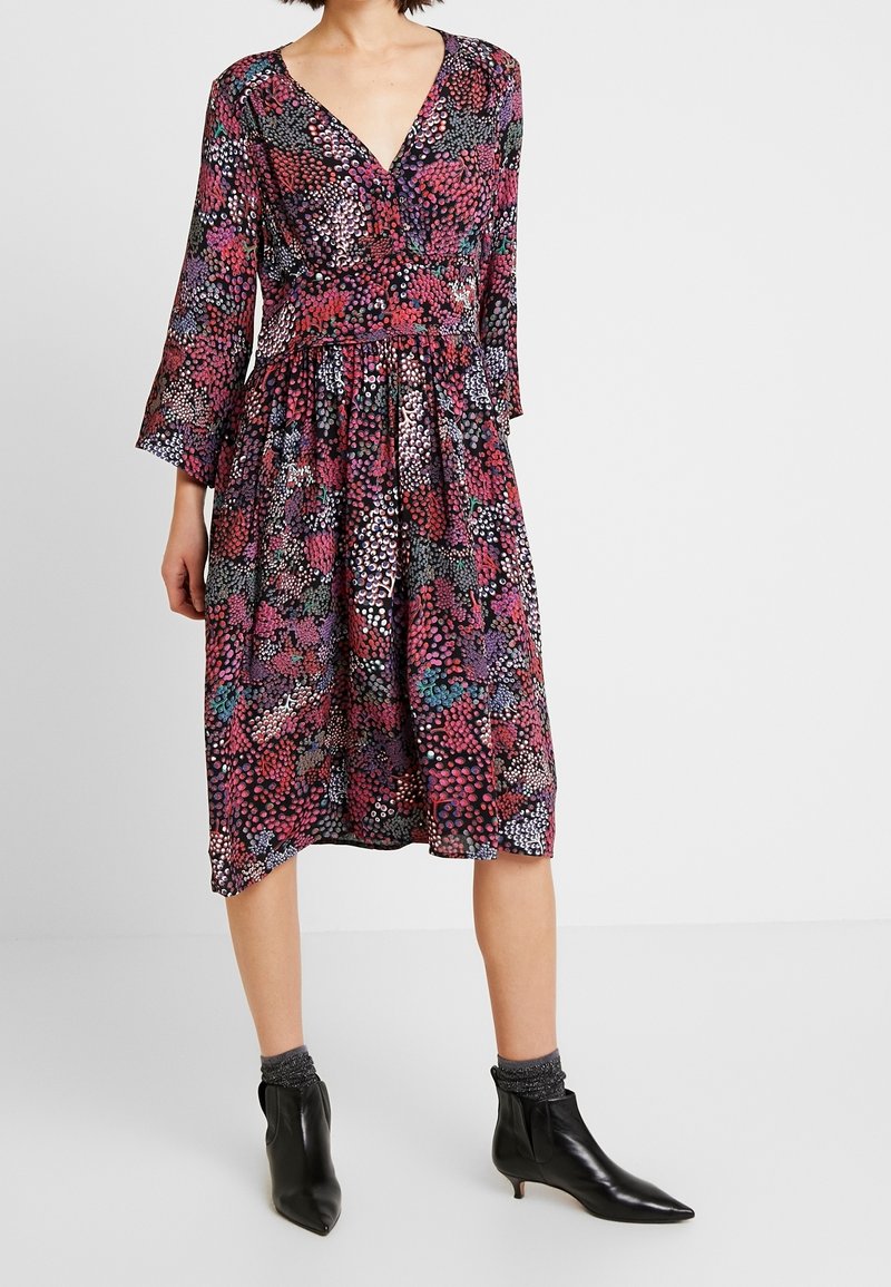 Robe à motif floral avec col en V, manches trois-quarts, taille cintrée et jupe fluide, dans des tons de rose, violet et noir.