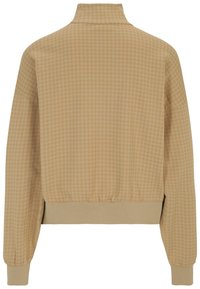 Giacca in twill di colore beige con motivo a pied de poule, colletto alto, polsini ed orlo elastici, caratterizzata da un taglio relaxed e una texture morbida.