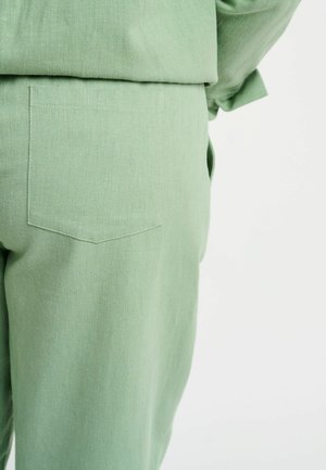 Kerged rohelised püksid tekstuurse kangaga, millel on tagakott terava klapiga. Lihtne disain, ilma nähtavate kinnituste või ehteta.