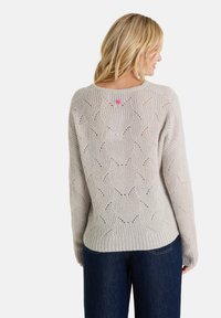 Hellgrauer gestrickter Pullover mit Wellenmuster, geripptem Saum und einem rosa Akzent auf der Rückseite. Weiche Textur mit lockerem Schnitt.