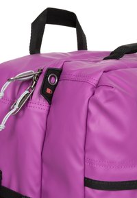 Fioletowy plecak wykonany z teksturowanego materiału nylonowego. Cechy to czarny uchwyt, suwaki oraz kontrastowe detale w szyciu.