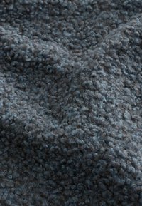 Měkká texturovaná tmavě šedá vlněná tkanina s hustým, smyčkovým vlasem vytvářejícím měkký a útulný povrch.