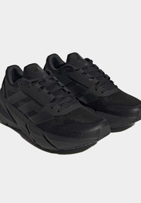 Black athletic shoes featuring a textured mesh upper, padded collar, lace closure, and a robust rubber sole with a shaped design.