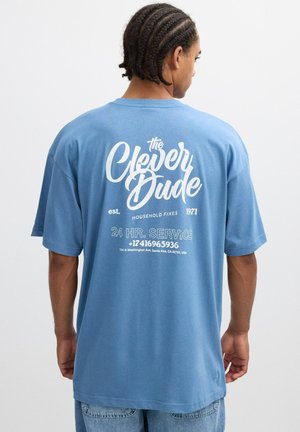 Camiseta de algodón azul con mangas cortas, con gran texto blanco en la parte trasera: "El Chico Listo", detalles del servicio y año de establecimiento 1971.