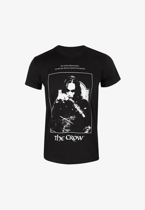 Sort bomuld T-shirt med hvidt grafisk tryk af en karakter, der holder et våben, med tekst over og "The Crow" nedenunder i fed skrift.