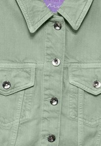 Veste en denim vert clair avec col, boutons-pression sur le devant et deux poches poitrine avec quincaillerie et détails de couture en ton argent.
