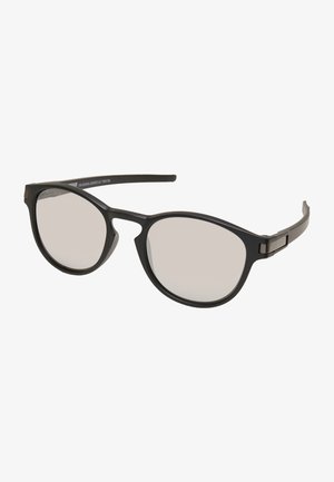 Sorte solbriller med en rund ramme, udstyret med klare linser og slanke sorte stænger. Inkluderer en diskret metalaccent på siden.