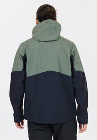 Vandtæt jakke med et to-farvet design, der har en lysegrøn øverste sektion og en marineblå nederste sektion. Hætte med justerbar krave.