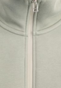 Ljusgrön zip-up jacka med hög krage. Slät tyg, med en off-white dragkedja och subtila sömmar för en figursydd silhuett.